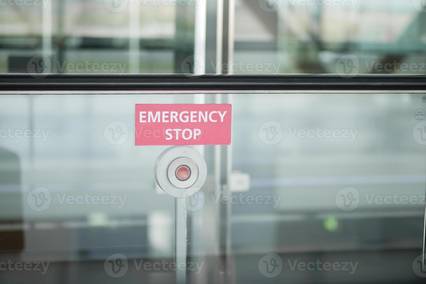 An emergency stop button is placed on a glass wall in a public space for safety measures photo