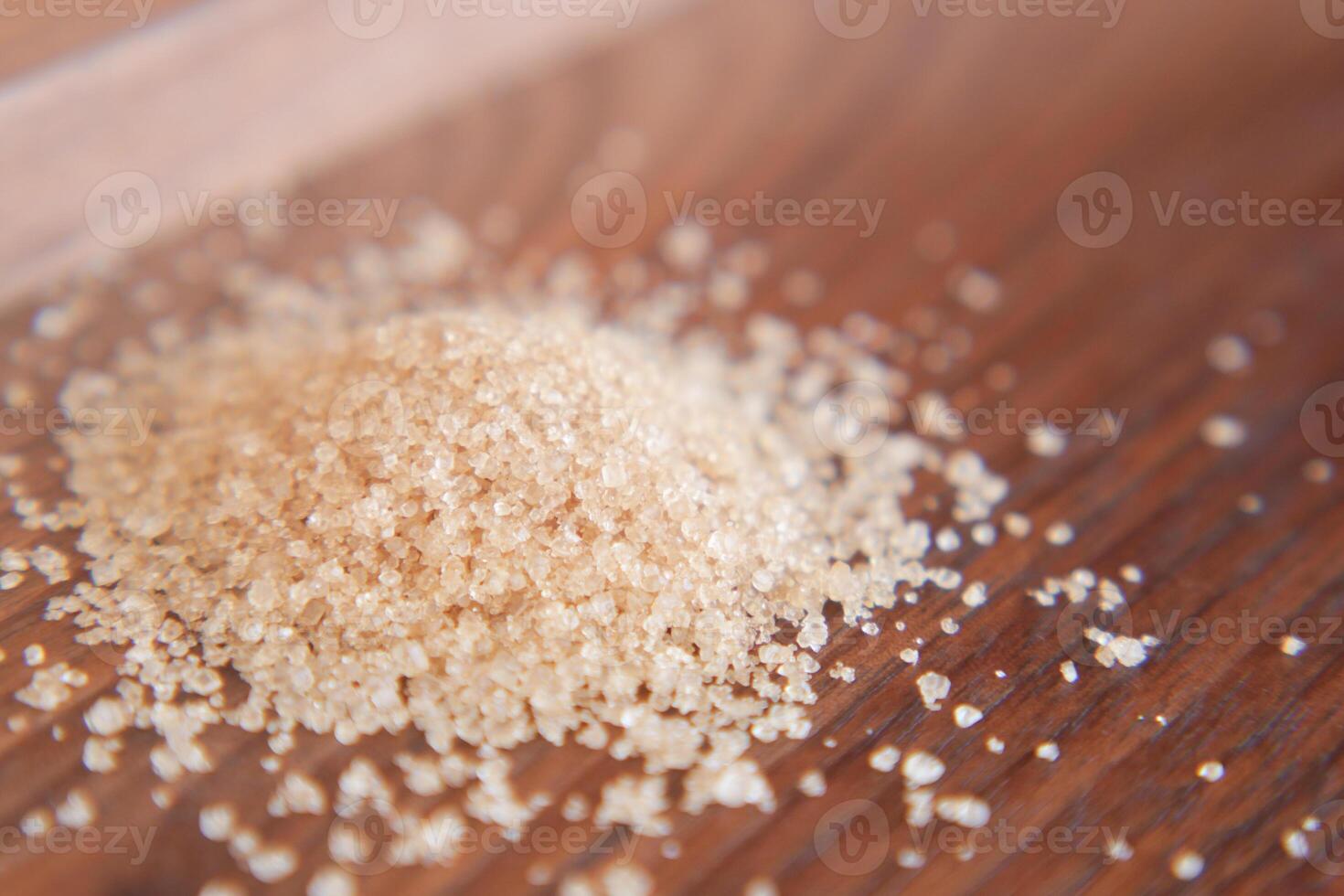 This image features a closeup view of a pile of brown sugar resting on a wooden surface photo