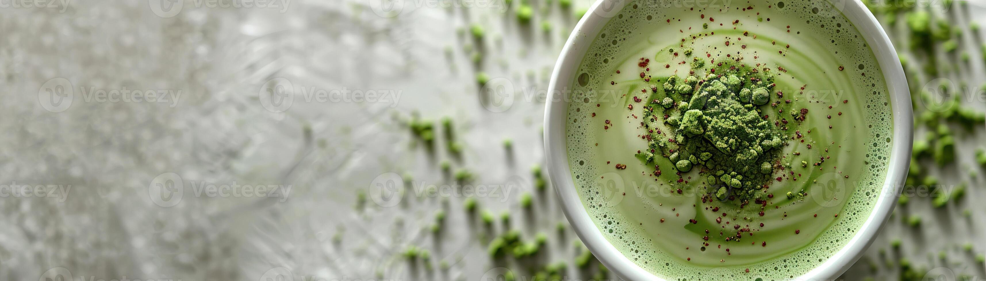 Matcha green tea latte in a white cup on a gray background with matcha powder spilled next to it. photo