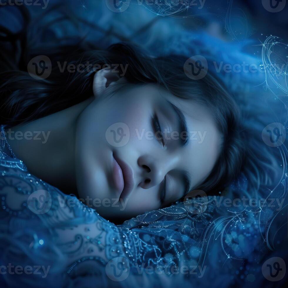 A beautiful woman with long dark hair is sleeping on a bed of blue flowers. She is wearing a blue dress and her eyes are closed. The background is a deep blue color. photo