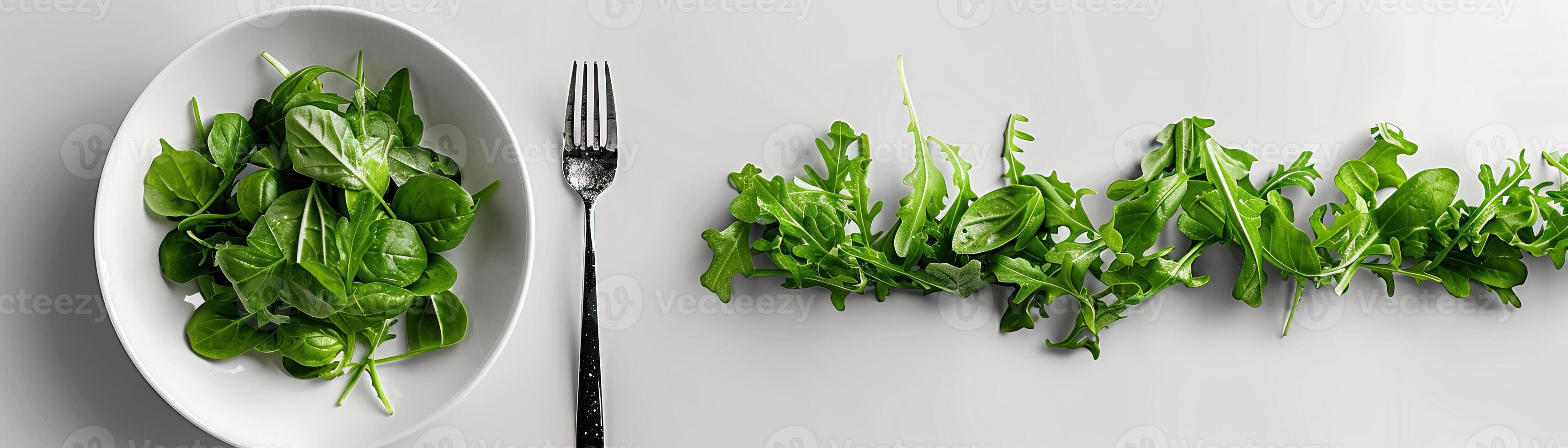 A white plate with a fork and a handful of salad greens. photo