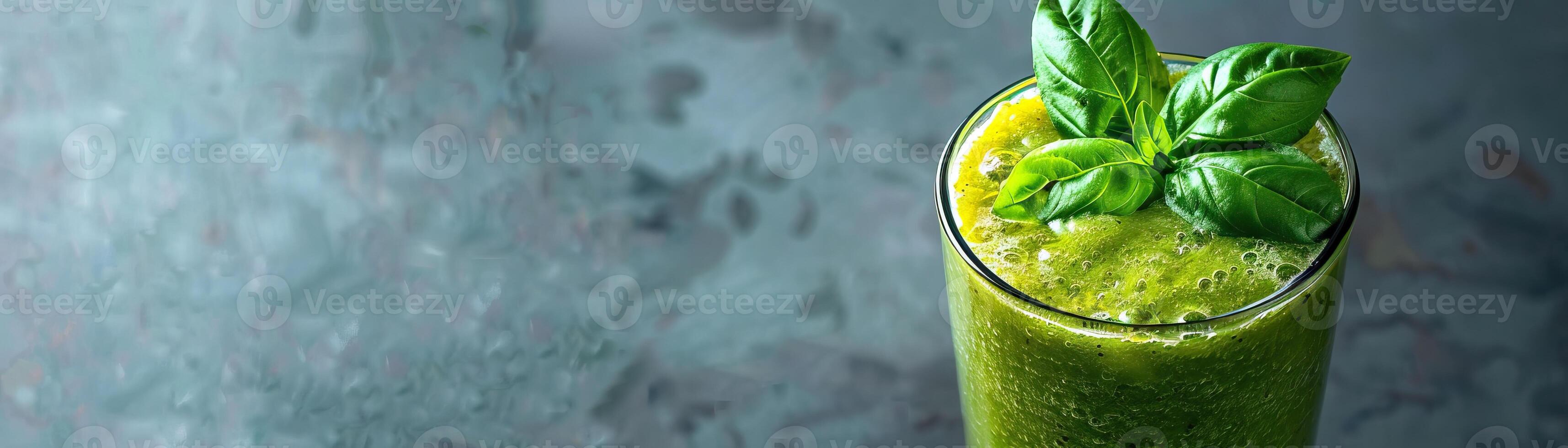 A glass of healthy green smoothie with basil leaves on a dark background. photo