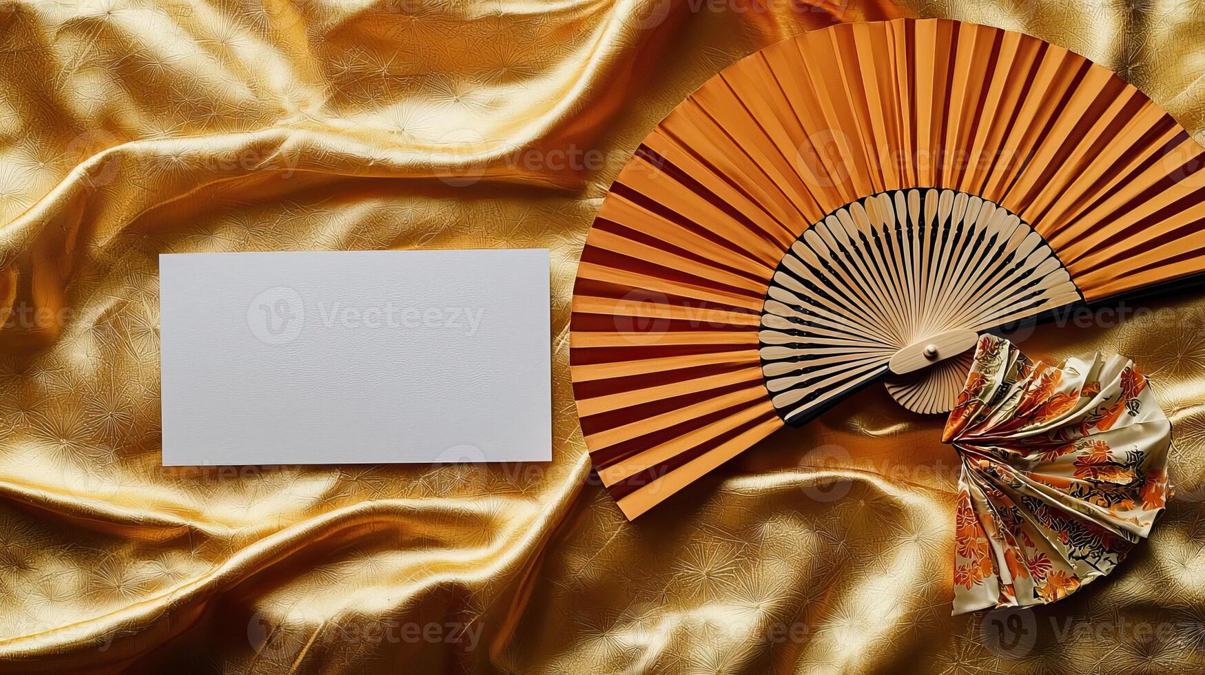 A mockup of a blank business card lying on golden Japanese silk, next to it lies a dancing Japanese fan photo