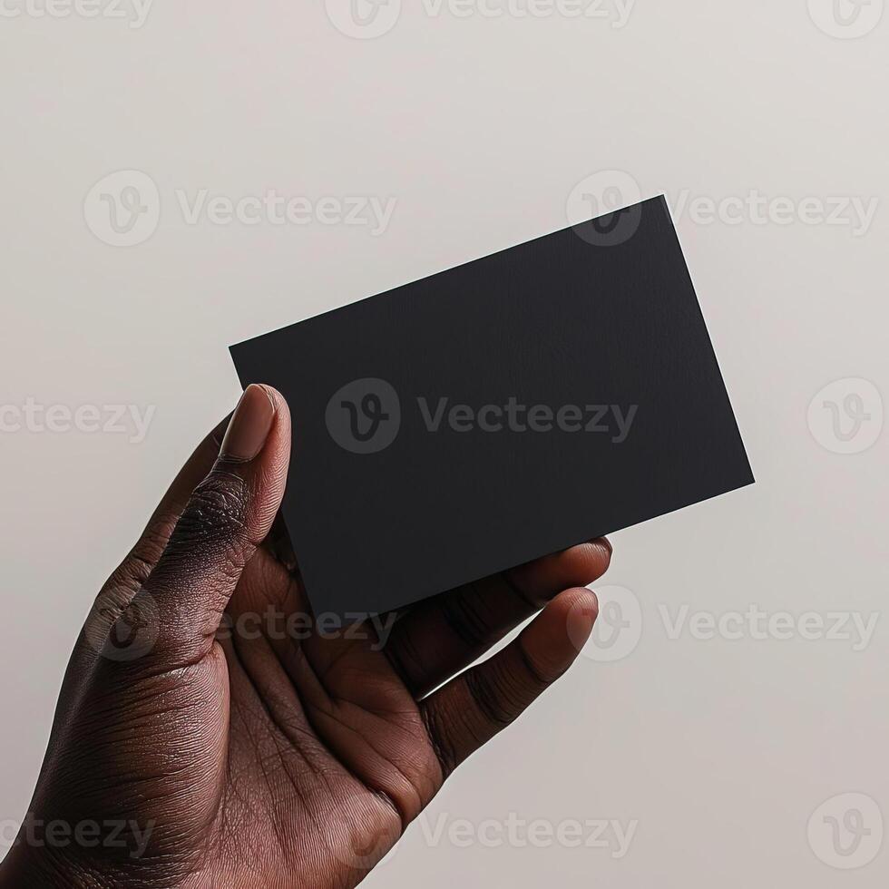 a dark skin hand holding a black blank business card The shot should be taken from a side perspective with the business card facing the camera photo
