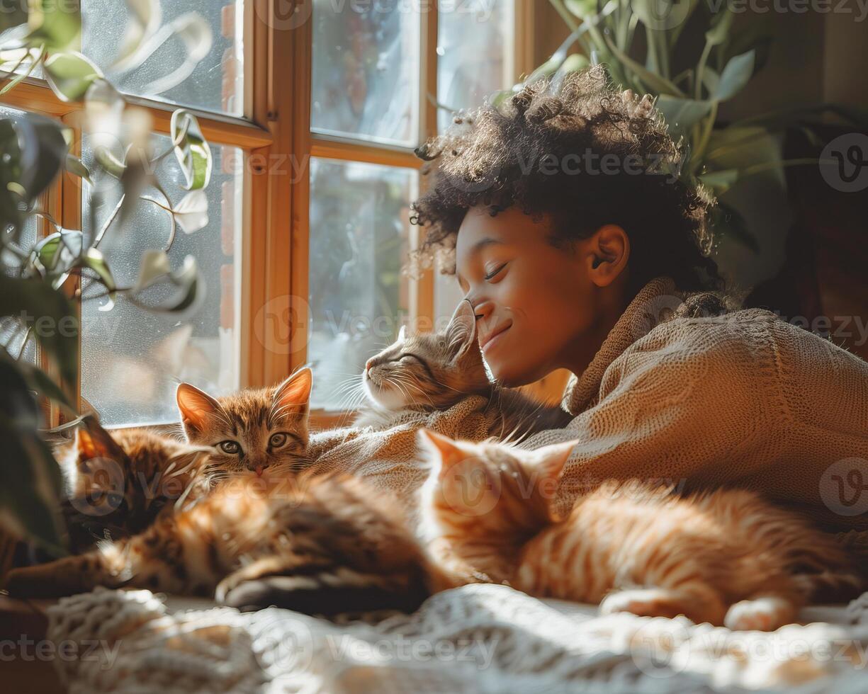 A young person enjoys a cozy afternoon with multiple cats lying on a blanket near a sunlit window surrounded by plants. photo