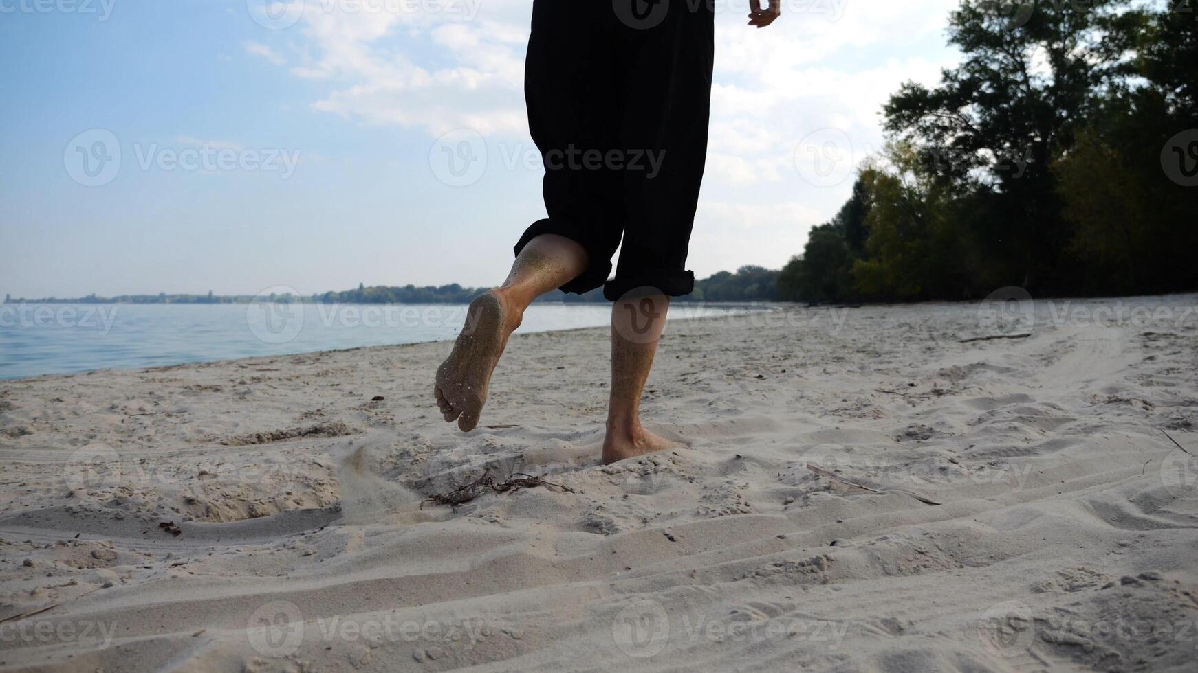 Bare feet of adult woman jogging on sand at the beach with seascape at background. Female legs running along sea shore. Happy lady spending time near ocean coast. Concept of summer vacation photo