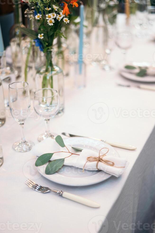 Table setting with napkin on empty white plate, wineglasses and cutlery on table, copy space. Place setting at wedding reception. Table served for banquet photo