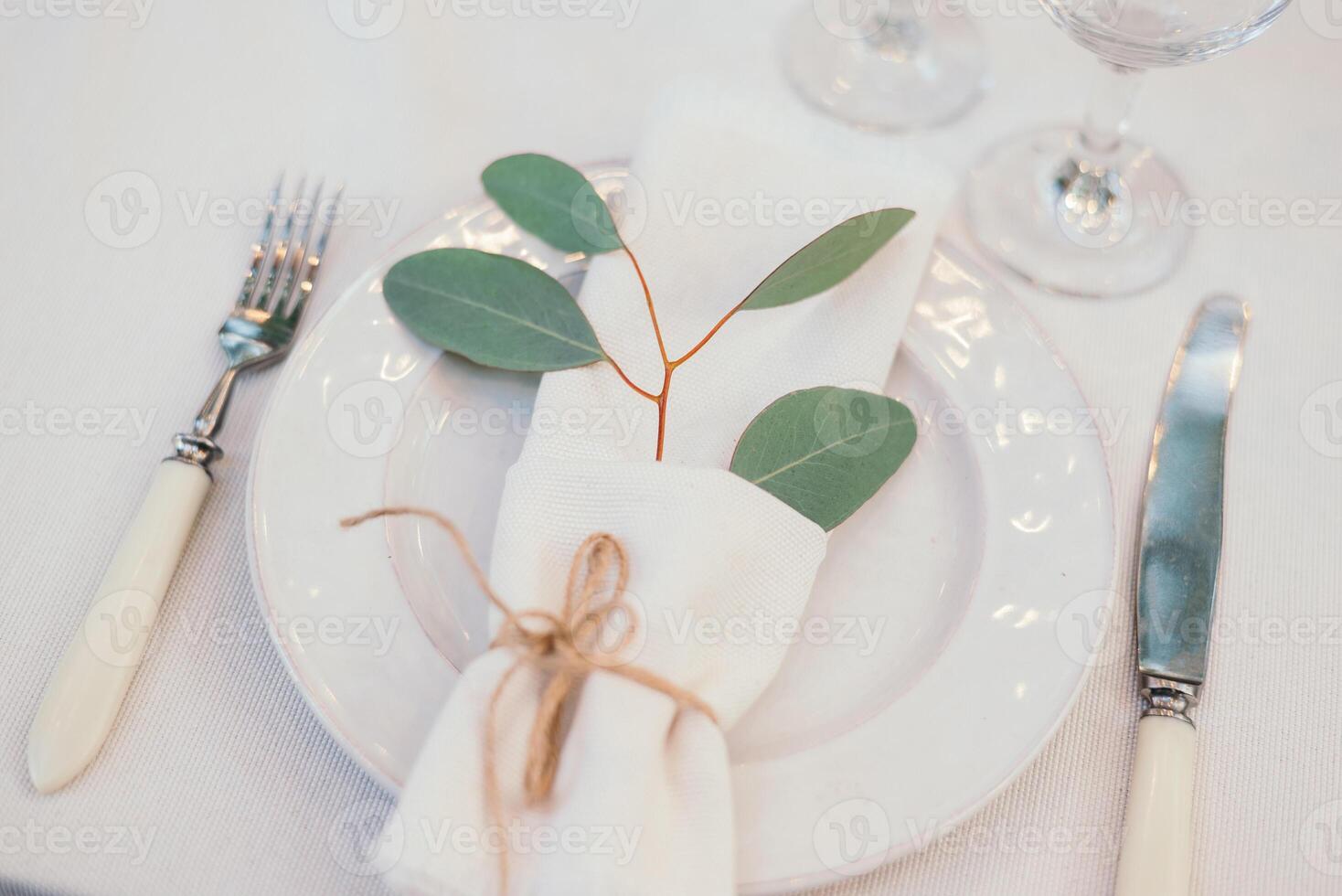 Table setting with napkin on empty white plate, wineglasses and cutlery on table, copy space. Place setting at wedding reception. Table served for banquet photo