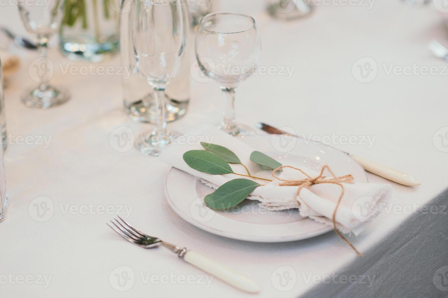Table setting with napkin on empty white plate, wineglasses and cutlery on table, copy space. Place setting at wedding reception. Table served for banquet photo
