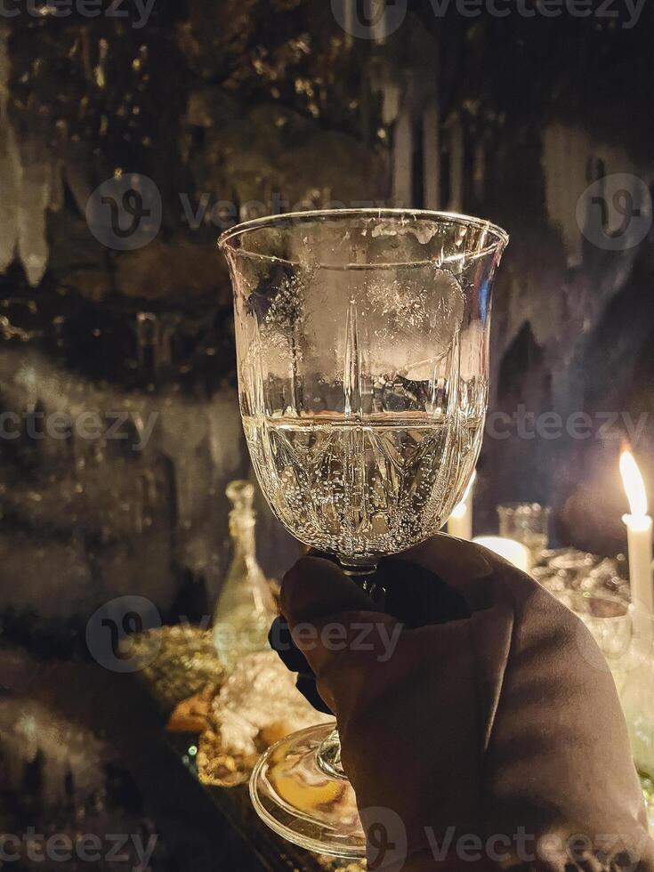 a person holding a glass of wine in front of candles photo