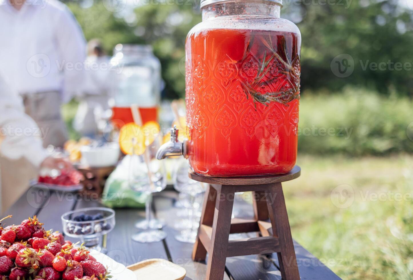 A wooden table with sweet berries and fruits, jars of freshly squeezed juice and empty glasses. photo