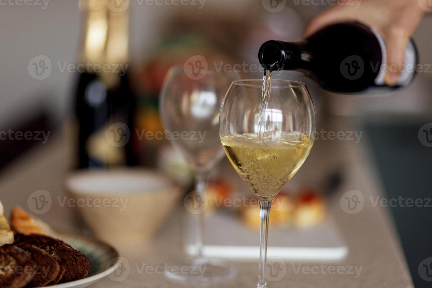 Close-up of an elegant glass with a long stem with champagne. The process of pouring sparkling wine into a goblet. photo