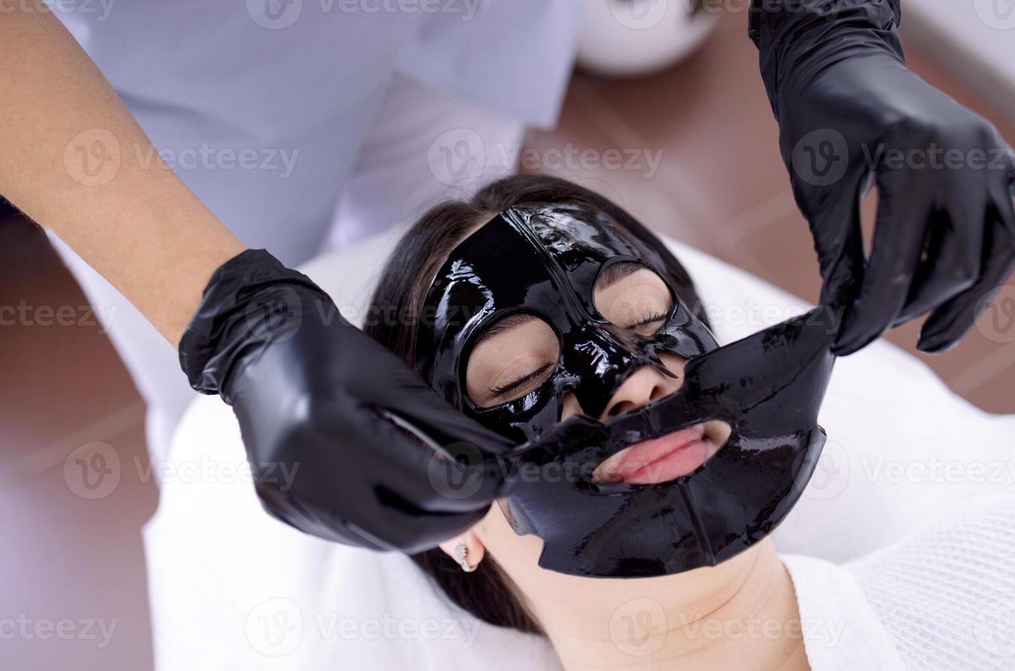 Beautiful caucasian woman with black silicone mask for the skin photo