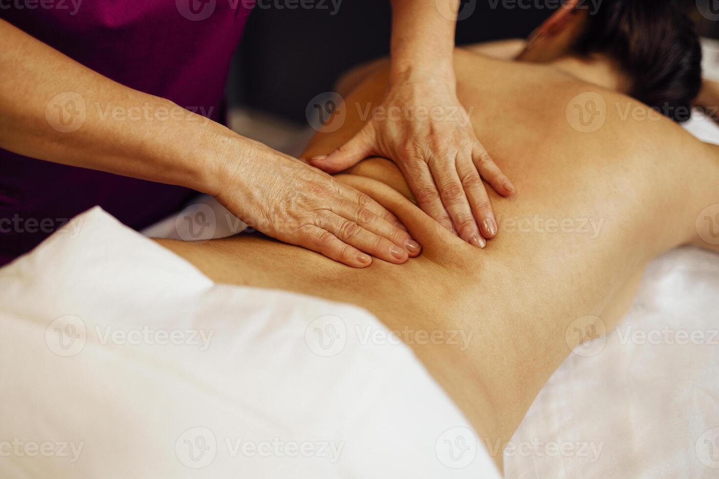 Happy young caucasian girl getting back massage in spa salon photo