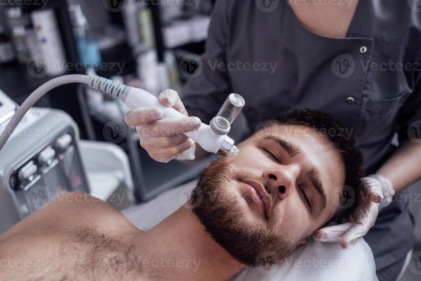 Caucasian man getting face peeling procedure in a beauty clinic, close up. photo