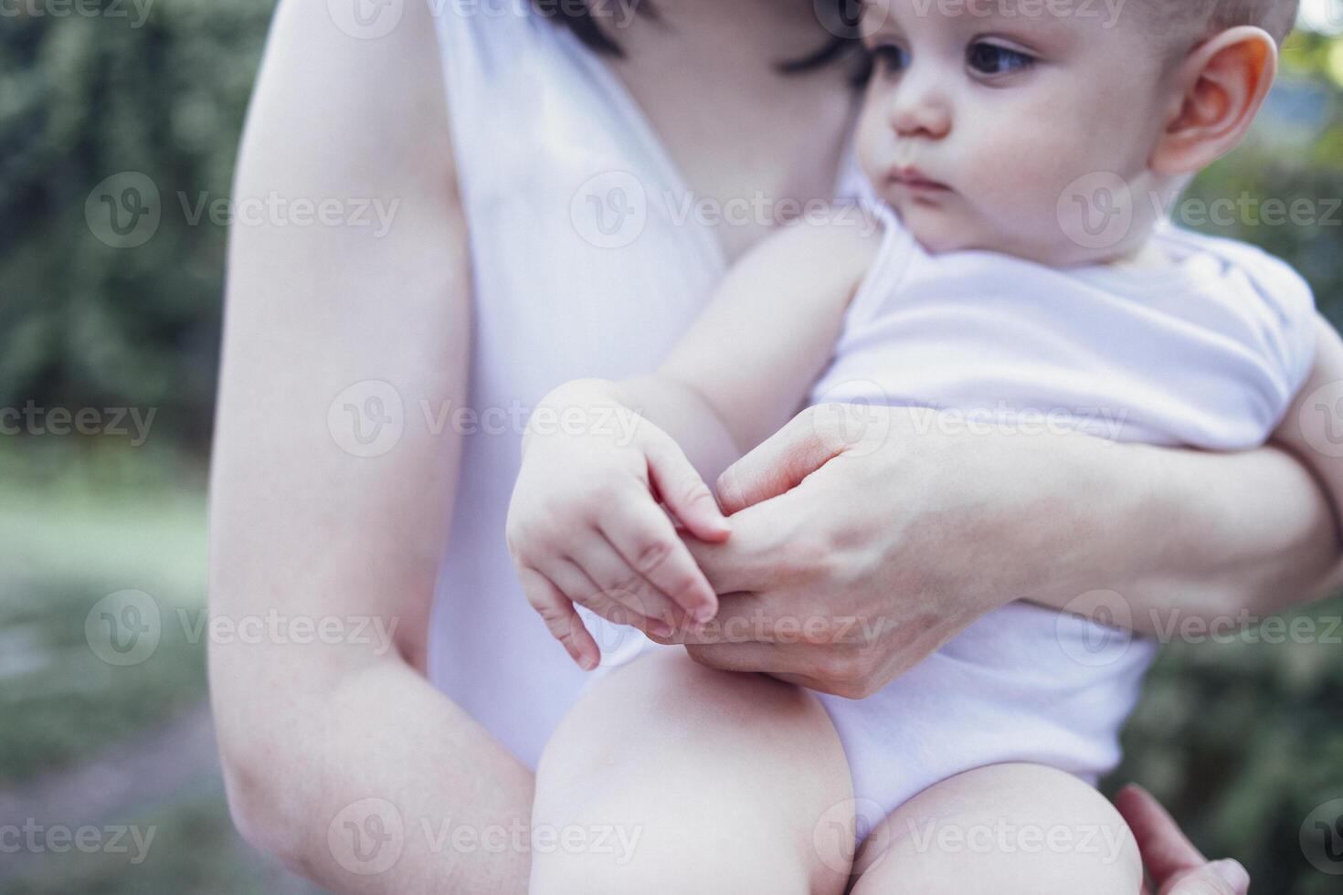 Close up of female portrait of young charming mother holds her cute baby in arms in garden photo