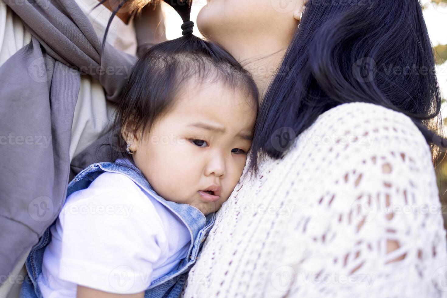 An Asian couple in love is kissing outdoors and holding their kid photo