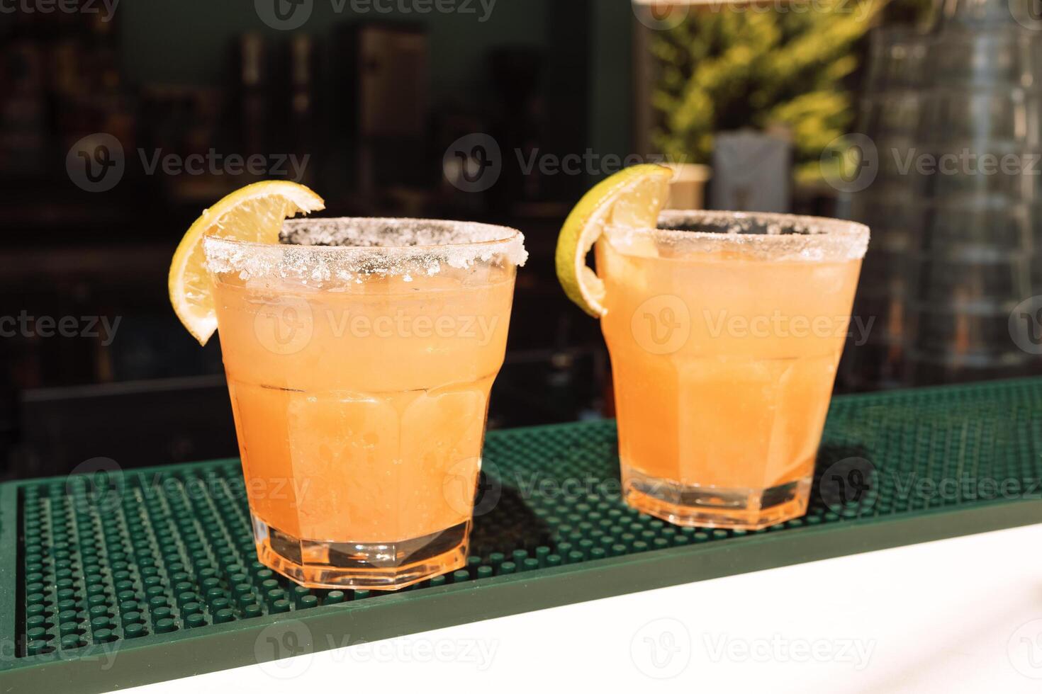 Two glasses with citrus cocktails on the bar. Chilled delicious drinks with lemon slices. photo