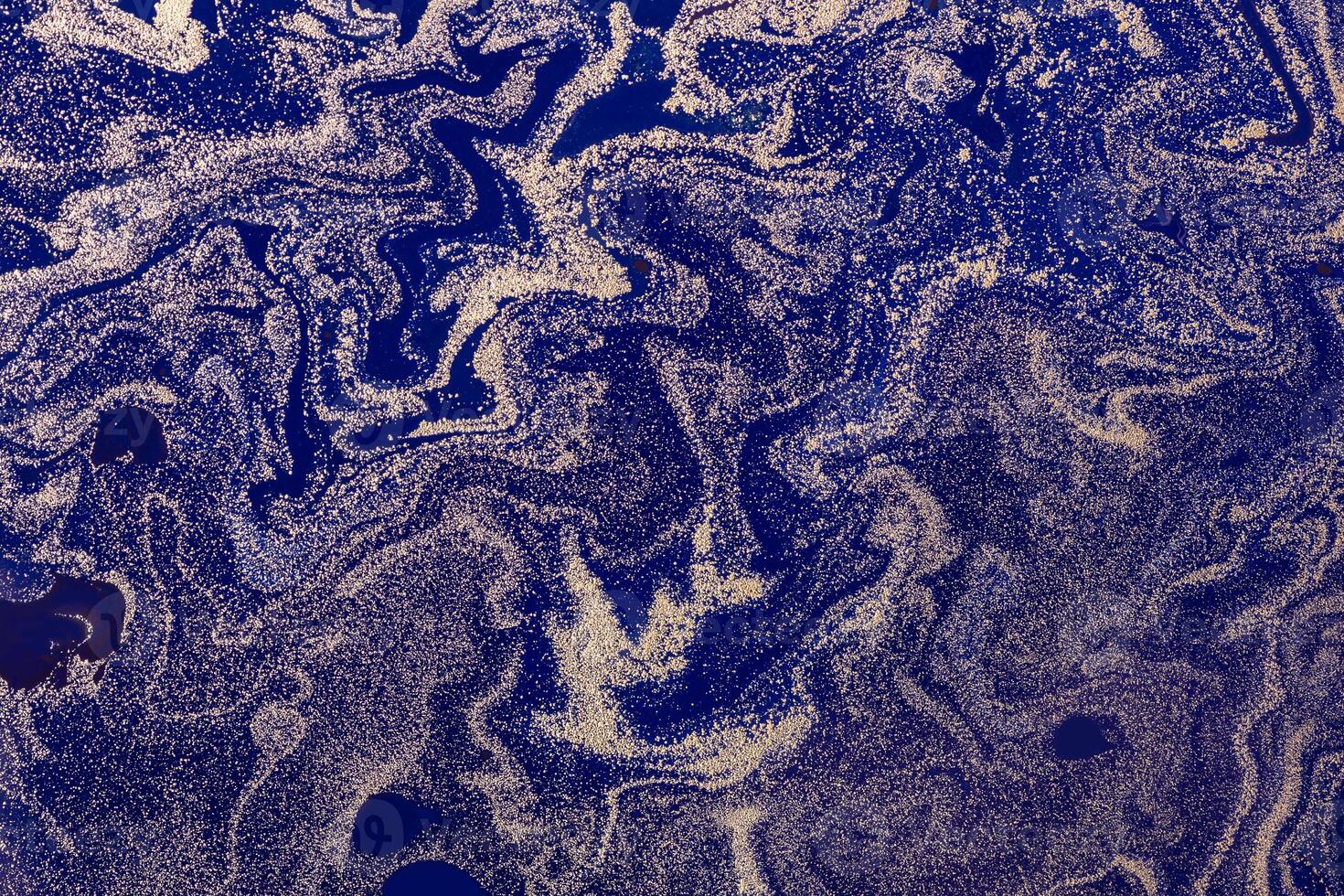 Gold spray particles pattern on dark blue background. Star dust. Abstract space background or texture. Acrylic Fluid Art photo
