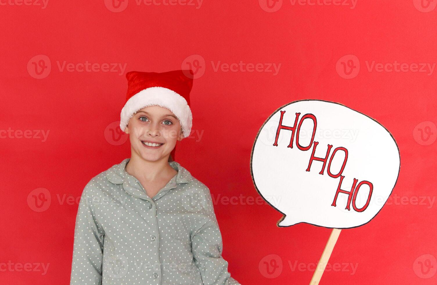 Merry Christmas and Happy New Year. Cute little girl in santa hat holding board with ho ho ho text photo