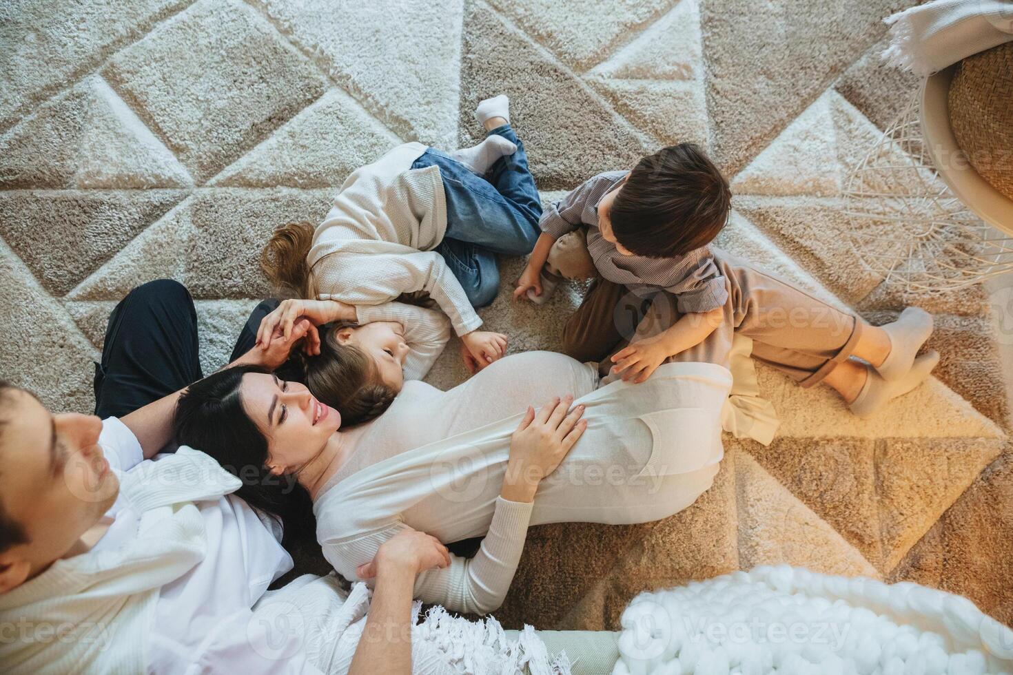 Family with two kids expect third child. Pregnant mother, father, son and daughter relaxing at home photo