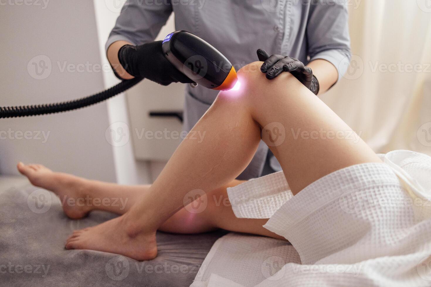 Shot of young fit brunette woman client receiving laser hair removal procedure on body photo