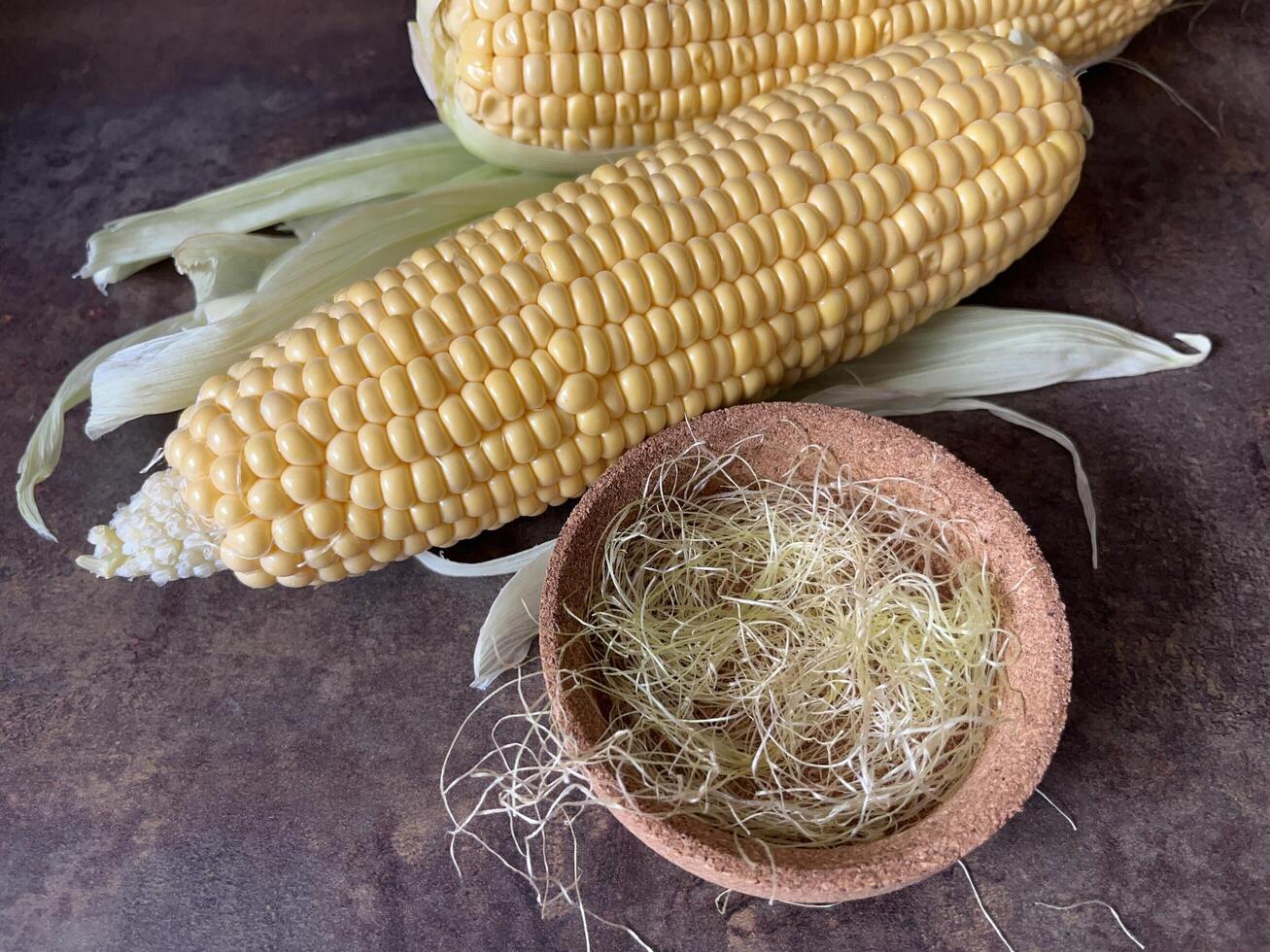 Close up corn hair in bowl and fresh corn. Corn hair has the benefit of lowering blood pressure, high cholesterol and arthritis photo
