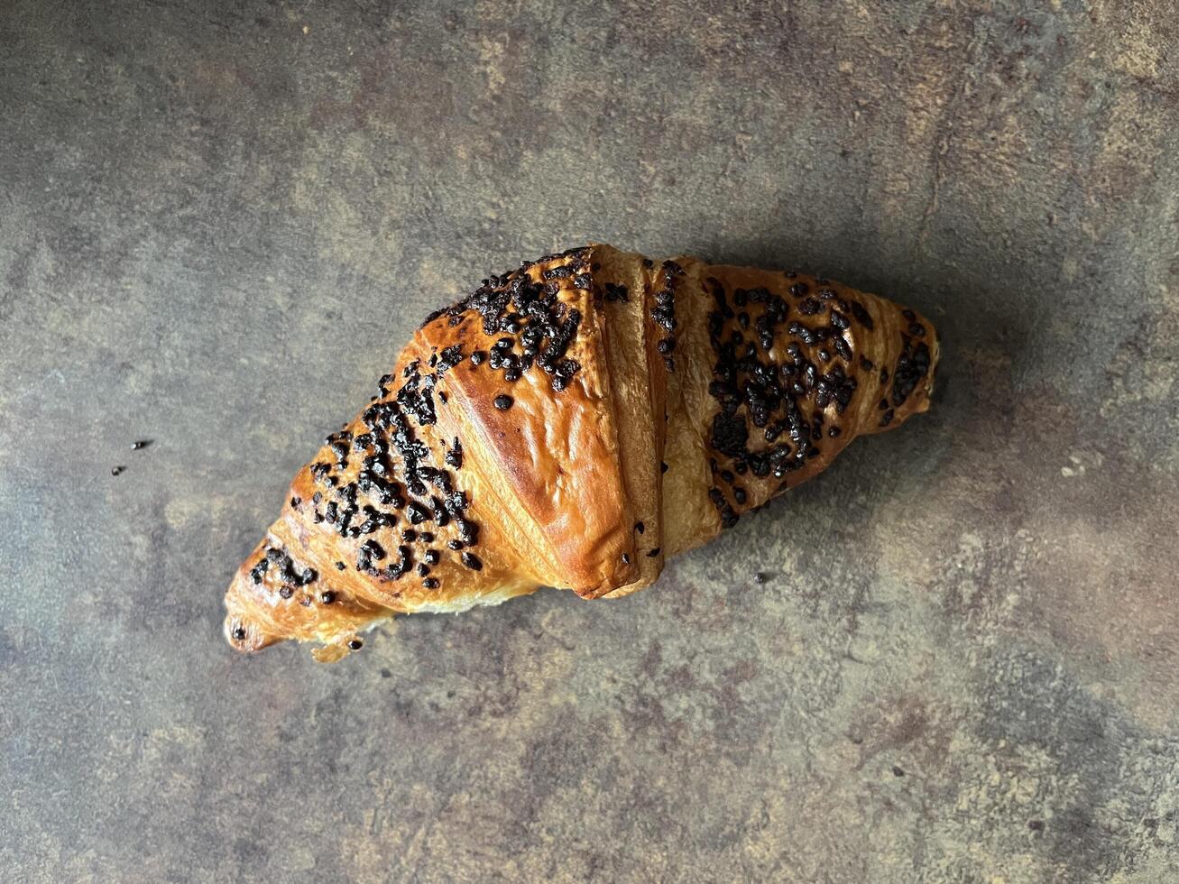 Delicious fresh chocolate croissant on dark background photo