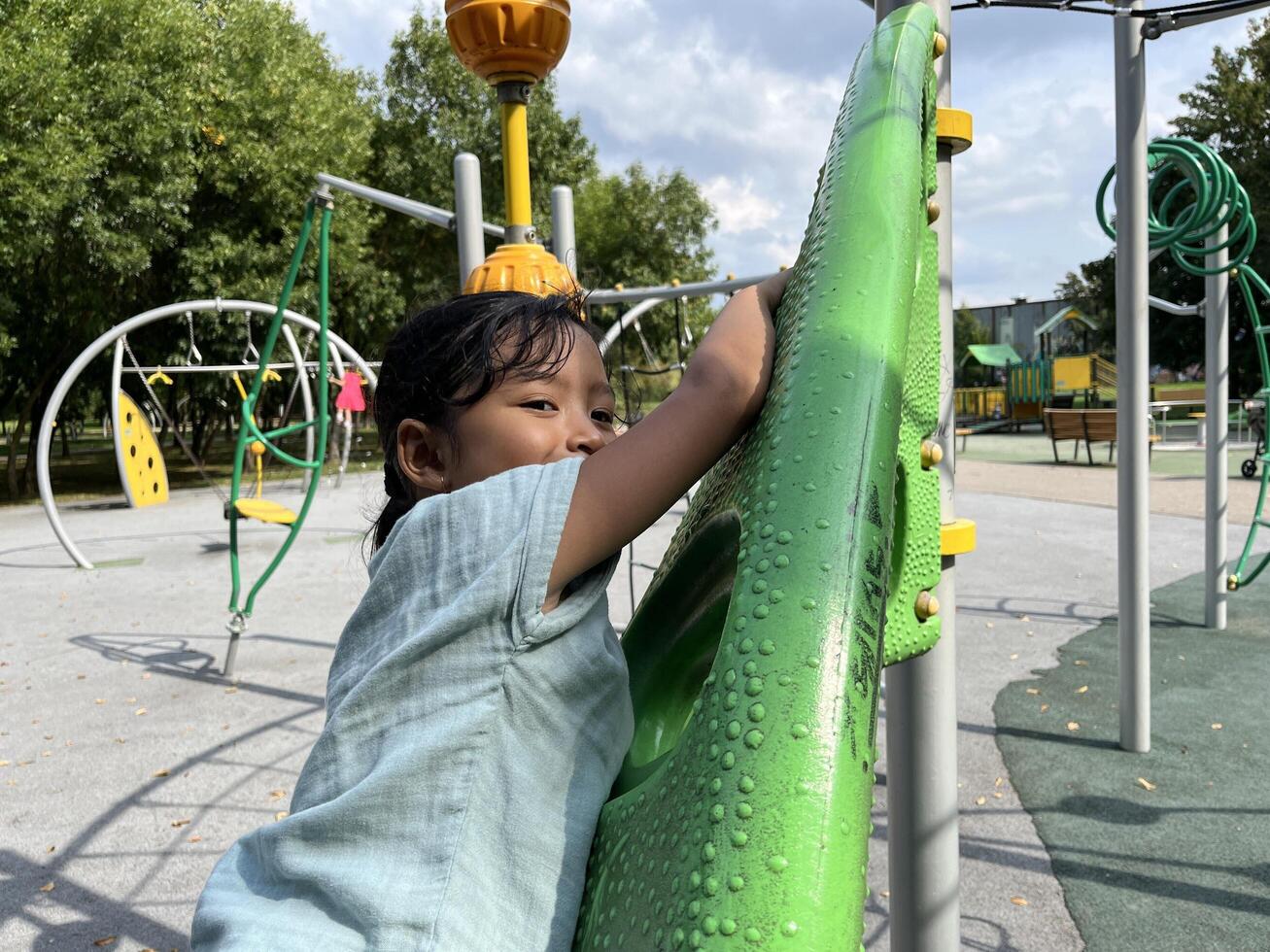 A happy young Asian little girl bravely climbing in the playground photo