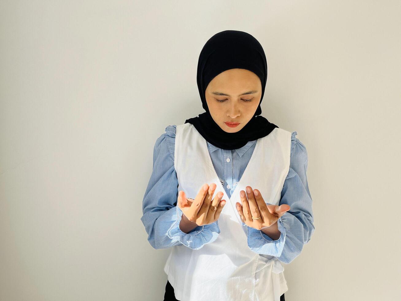 Portrait of young muslim woman making dua gesture with her hands photo