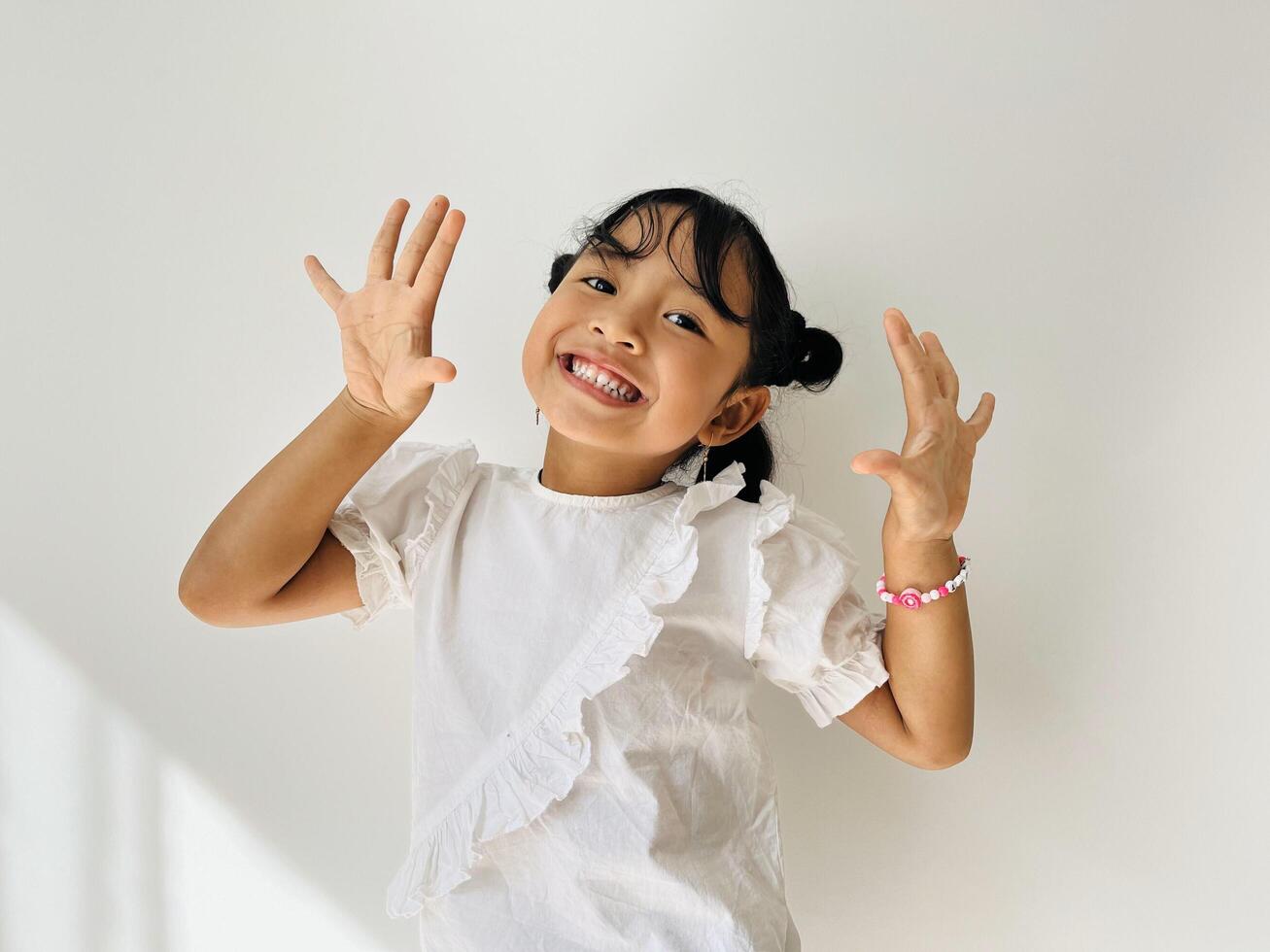 Cute Asian little girl wearing white shirt looking at the camera with cute pose. Happy kids concept photo