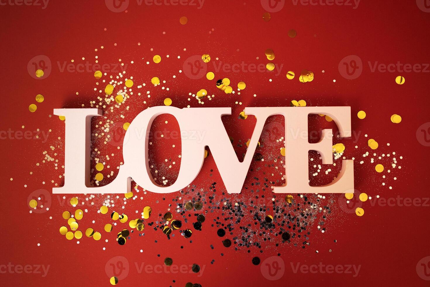 Close up of the word Love on a red background. Bright backdrop with silver sequins and golden round confetti. photo