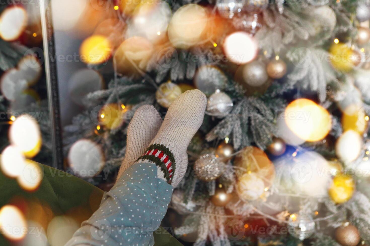 Woman in warm knitted socks relaxing near Christmas tree. Cozy xmas background with female legs photo