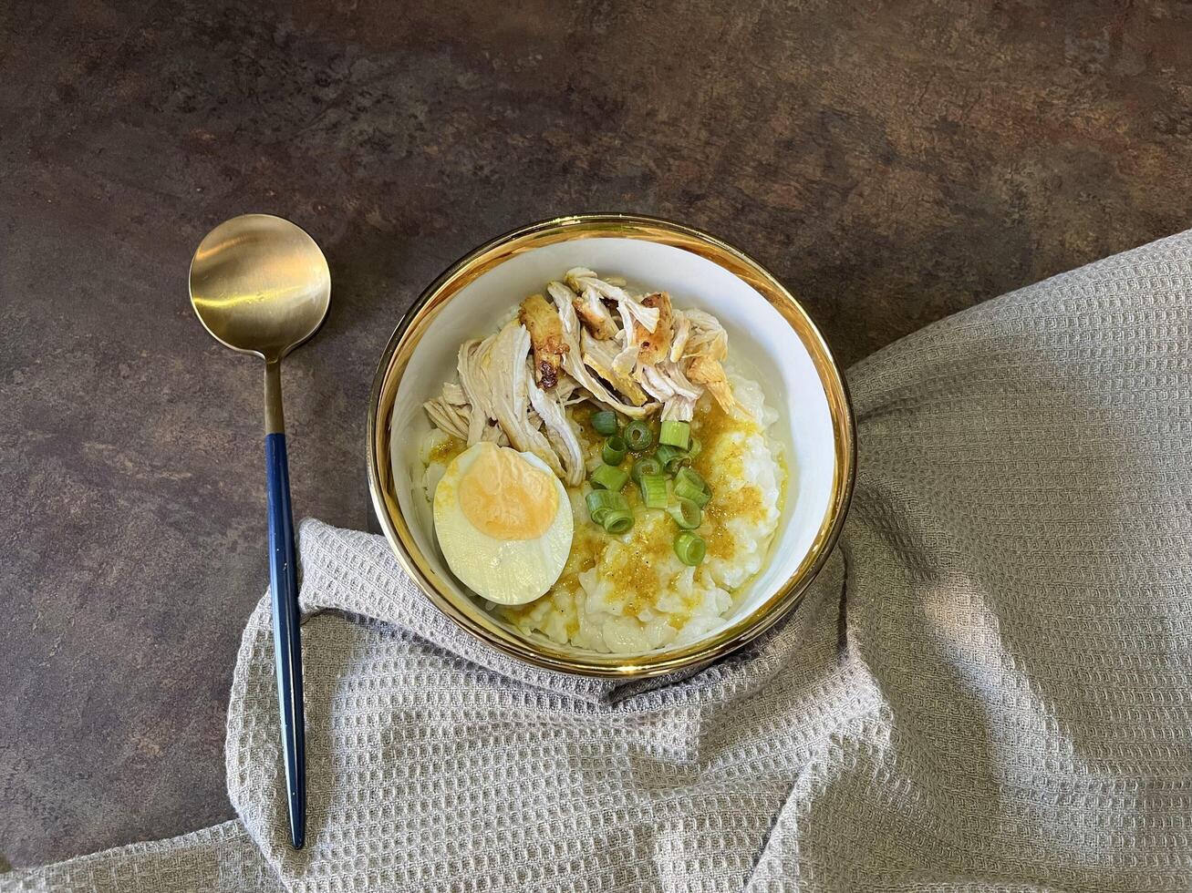 Bubur ayam is an Indonesian chicken congee. It is rice congee cooked with coconut milk served with shredded chicken meat chopped scallion, boiled egg, topped with yellow chicken broth photo