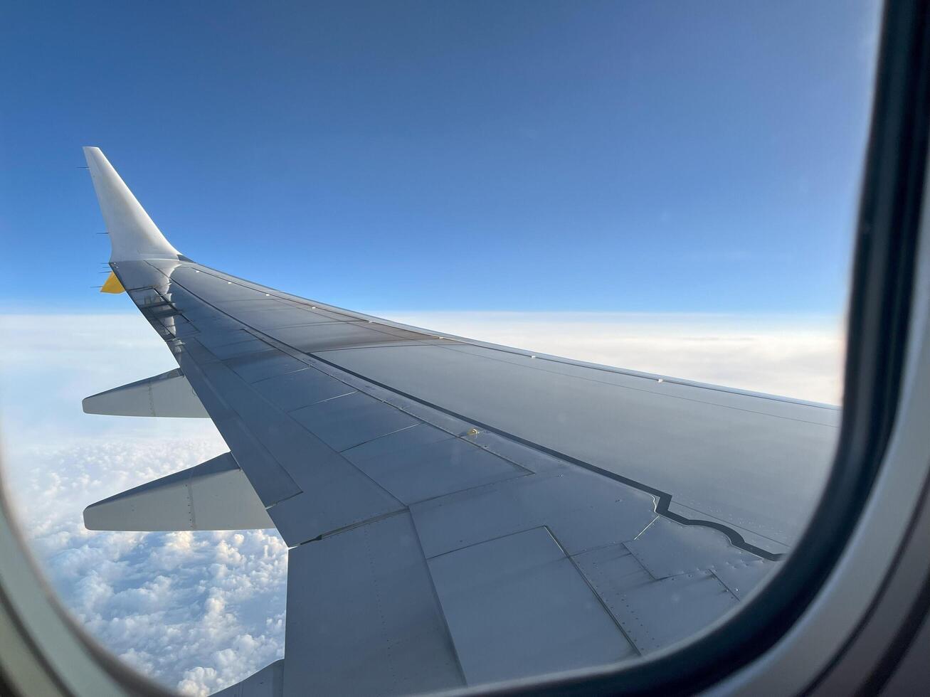 View from the airplane window at a beautiful cloudy sky and the airplane wing. Sky seen through window of an airplane. photo