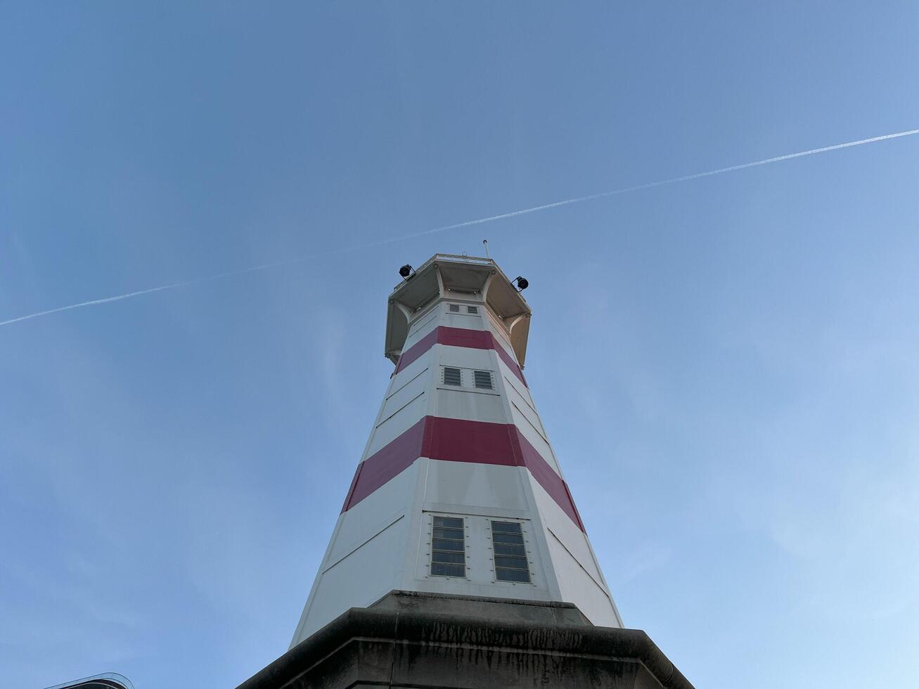 Lighthouse with clear blue sky in evening with flight path photo