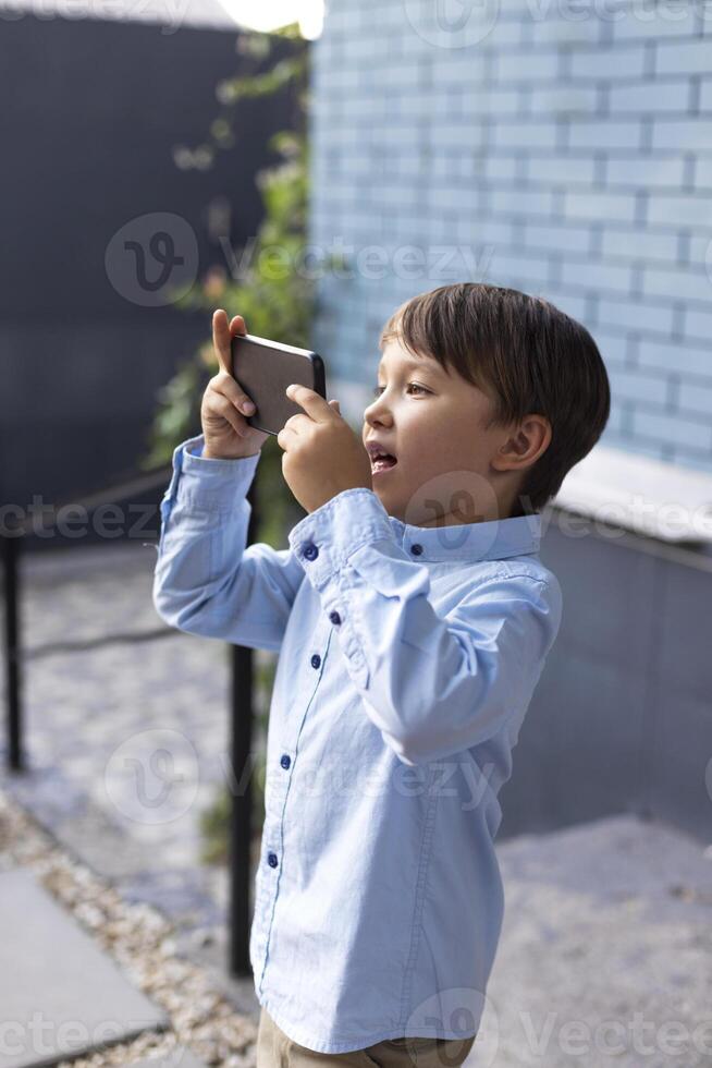 Littlee boy takes pictures of the summer celebration on a smartphone photo