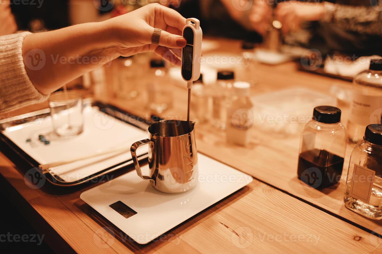 Master class of creating candles. Closeup of woman hand measuring temperature of melted wax. photo