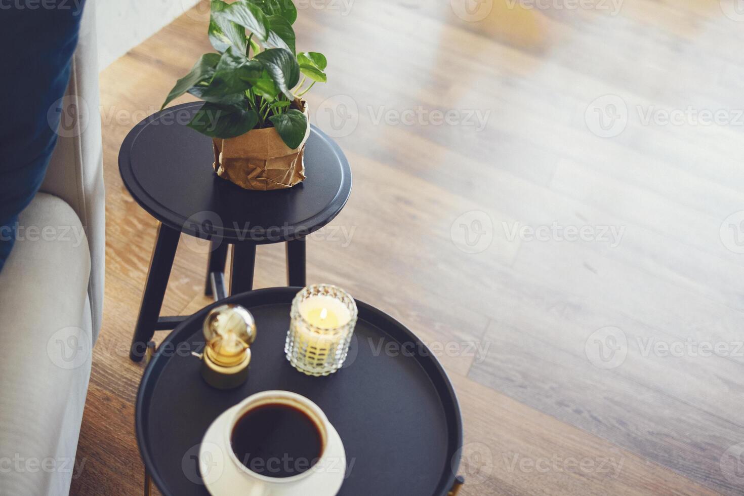 Large white cup of coffee and lit scented candle on round black coffee table. photo