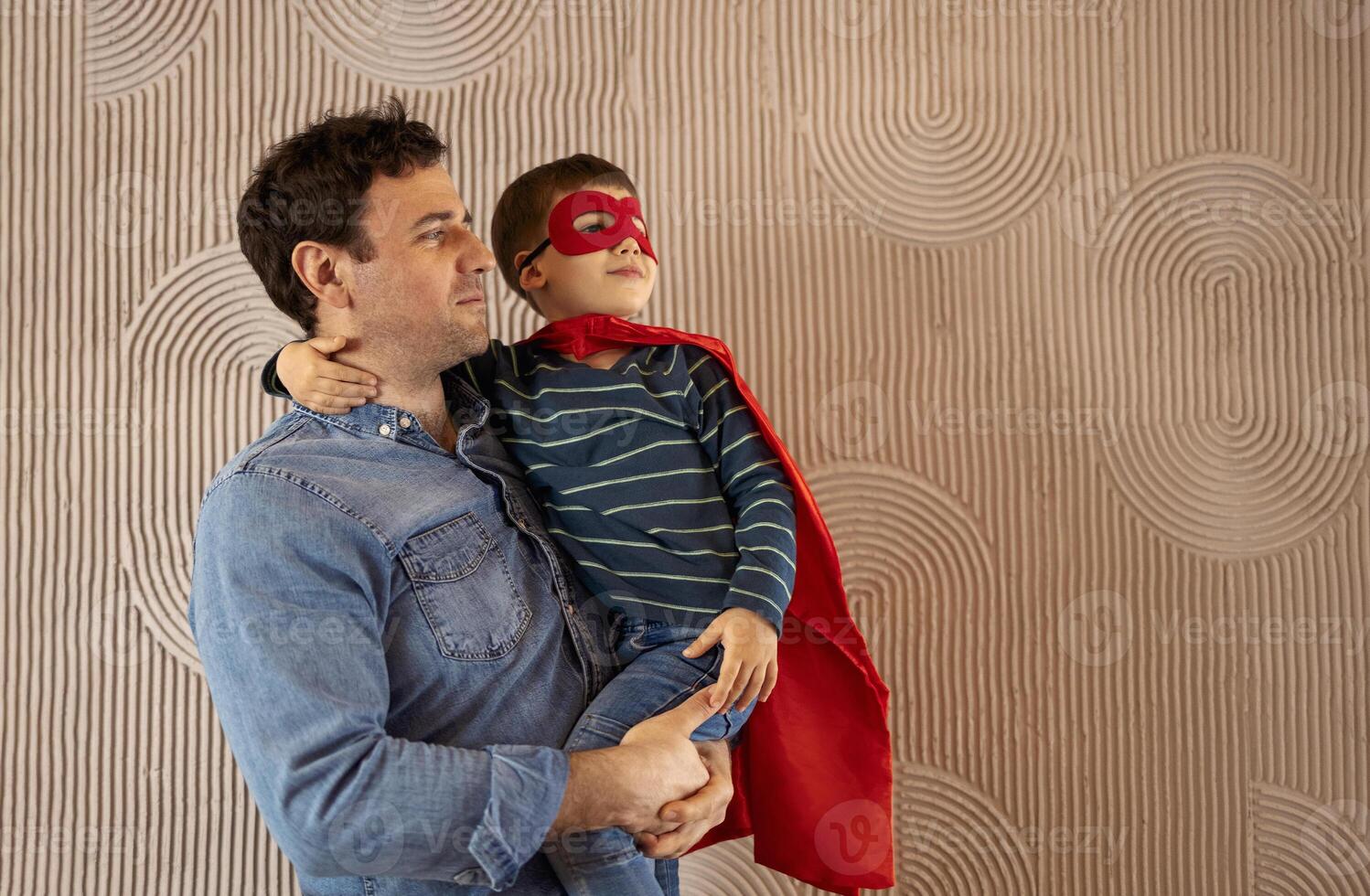 Joyful daddy carries small child who embraces him and smiles happily photo