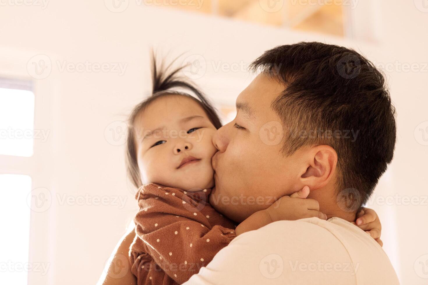 A young Korean father is holding his cute daughter in his arms photo