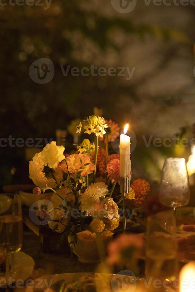 Wedding table for guests, decorated with candles, are served with cutlery and crockery and covered with yellow tablecloth photo