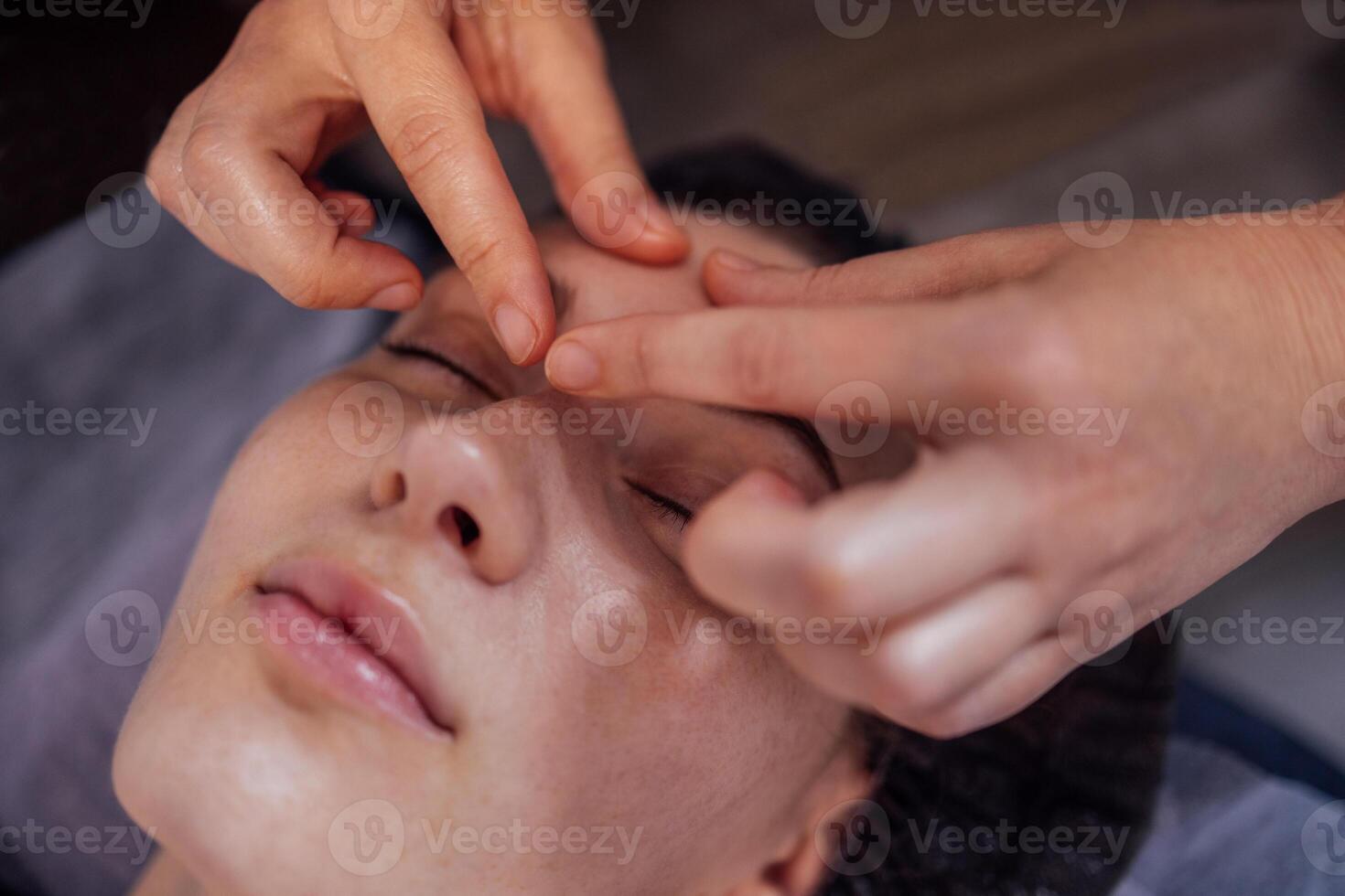 Close up portrait of a young attractive woman getting facial massage. photo