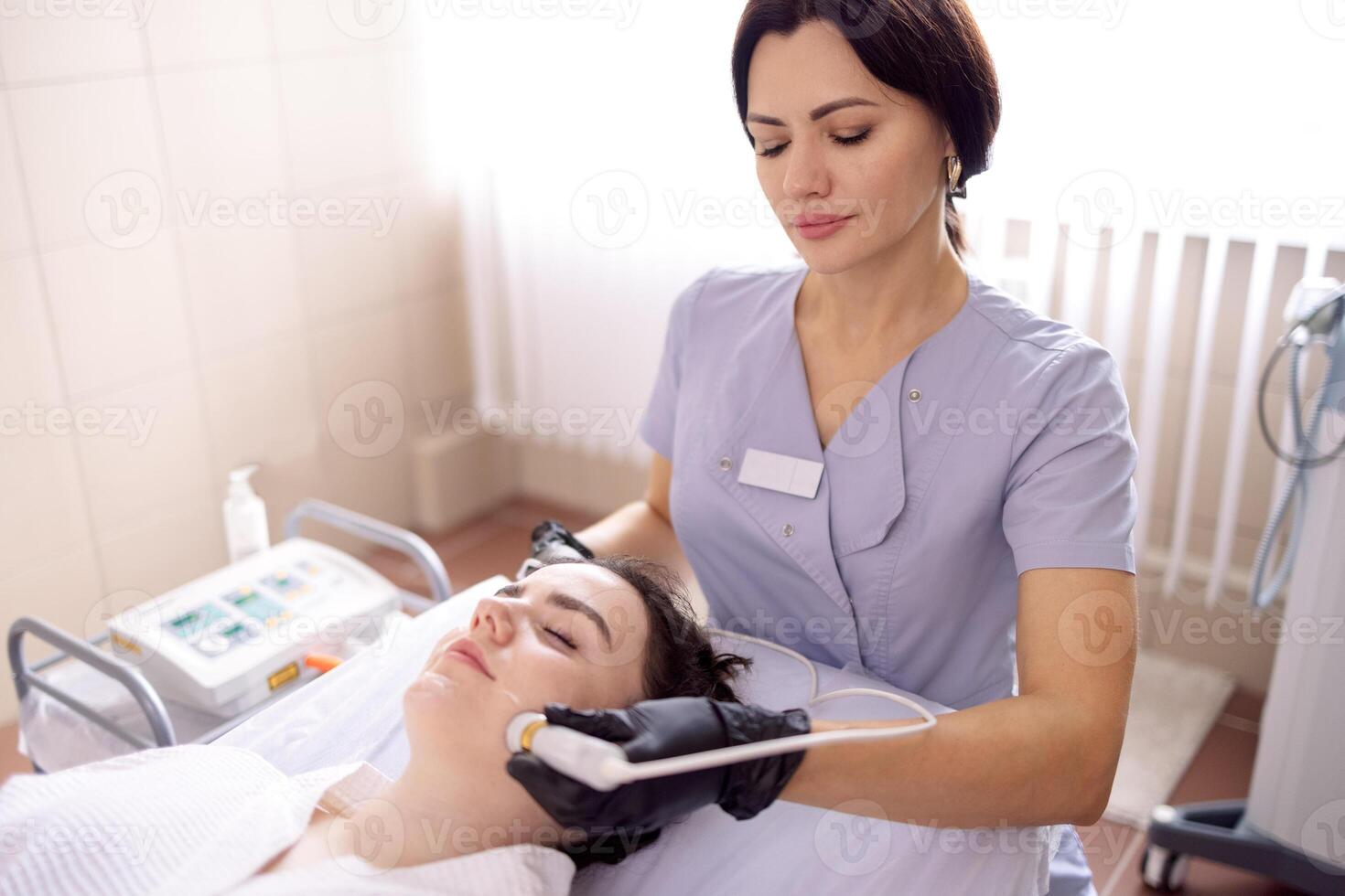 Closeup of face of beautiful relaxing girl undergoing hardware cosmetology procedure in spa photo