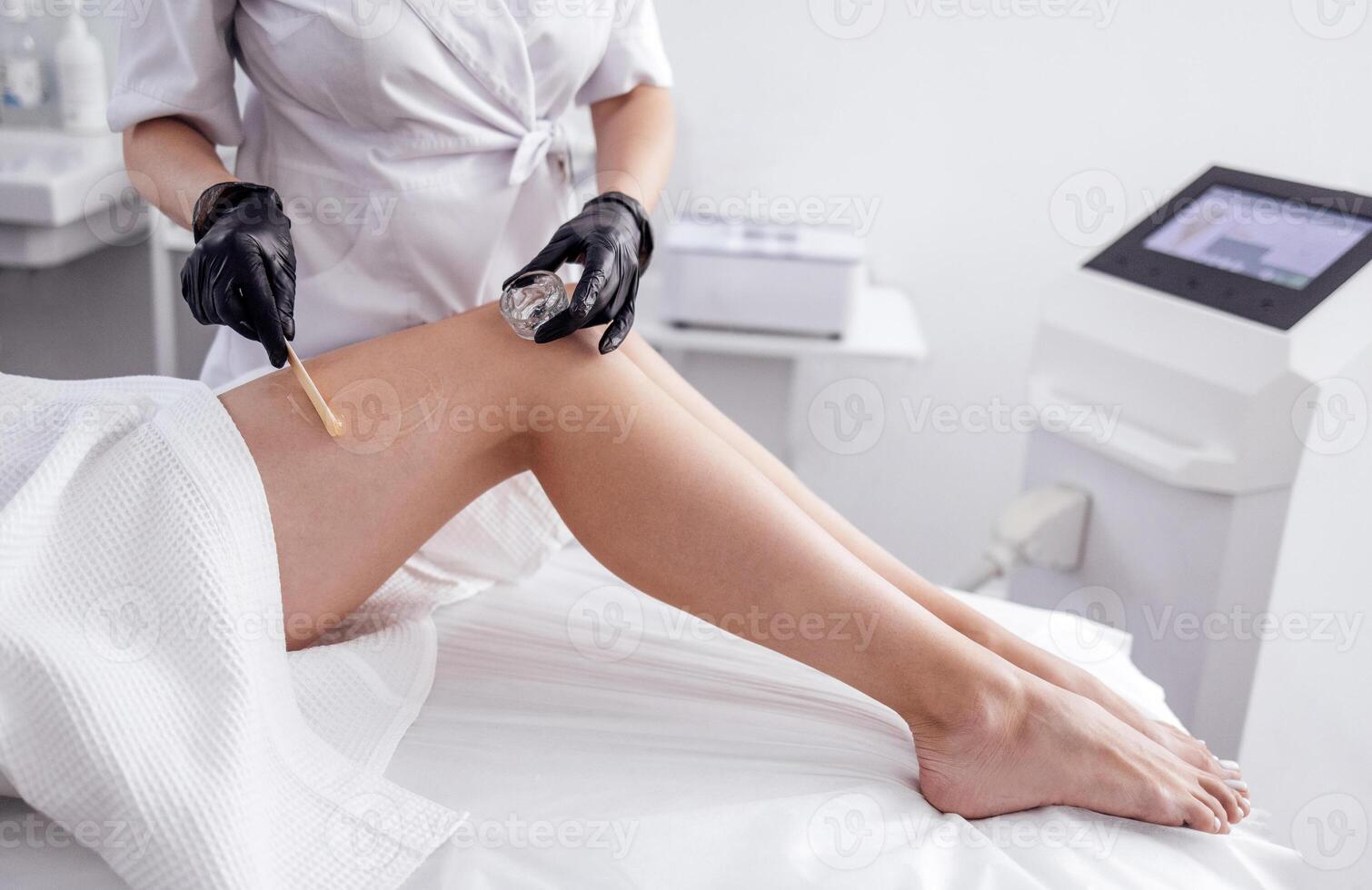 Preparation of clients legs before laser hair removal procedure in spa salon photo