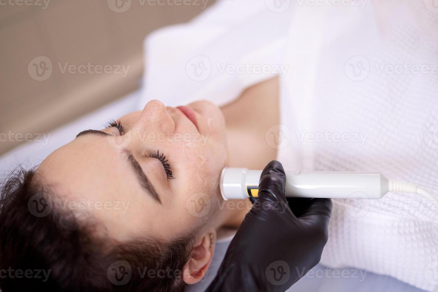 Closeup of face of beautiful relaxing girl undergoing hardware cosmetology procedure in spa photo