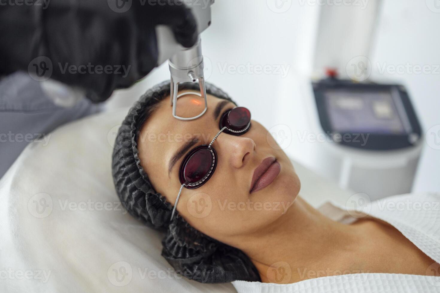 Closeup of the face of young woman undergoing laser resurfacing and peeling procedure in spa salo photo
