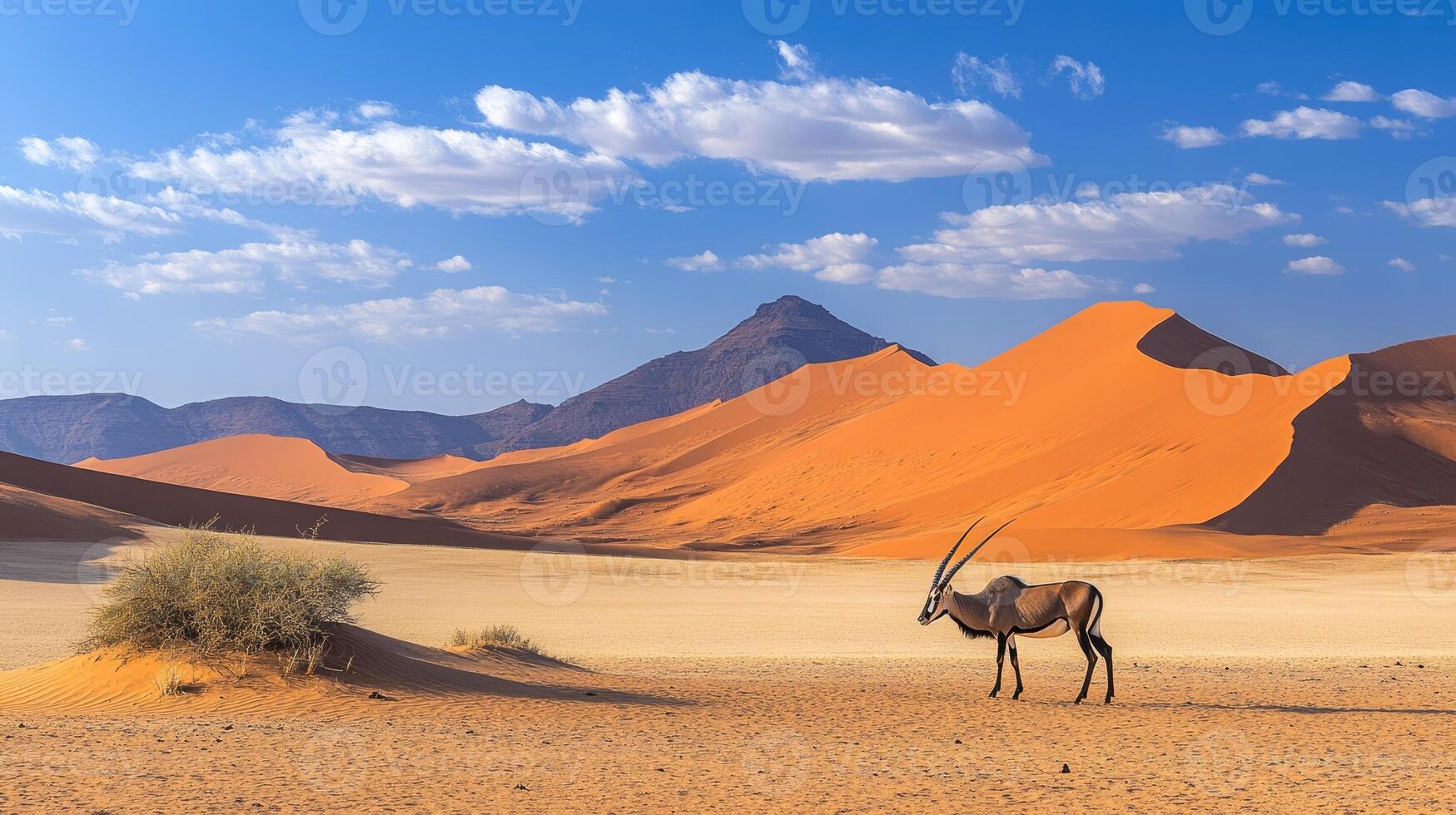 A majestic antelope with long horns stands gracefully atop sand dunes photo