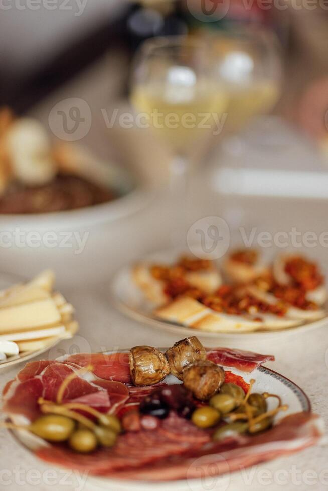 Two glasses of cool champagne and plates with various snacks on a table photo