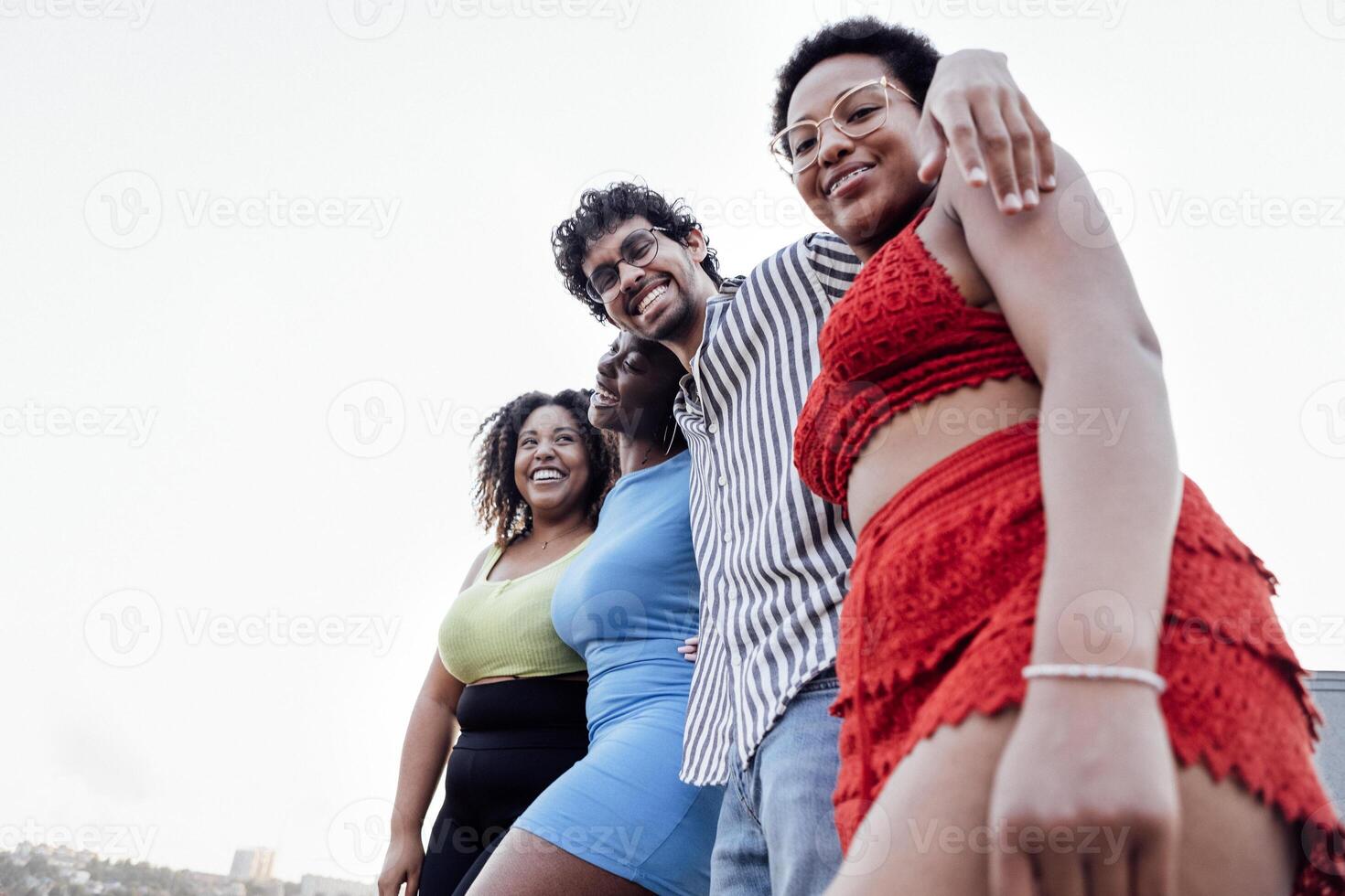 Four smiling mixed race friends standing and looking down at camera photo